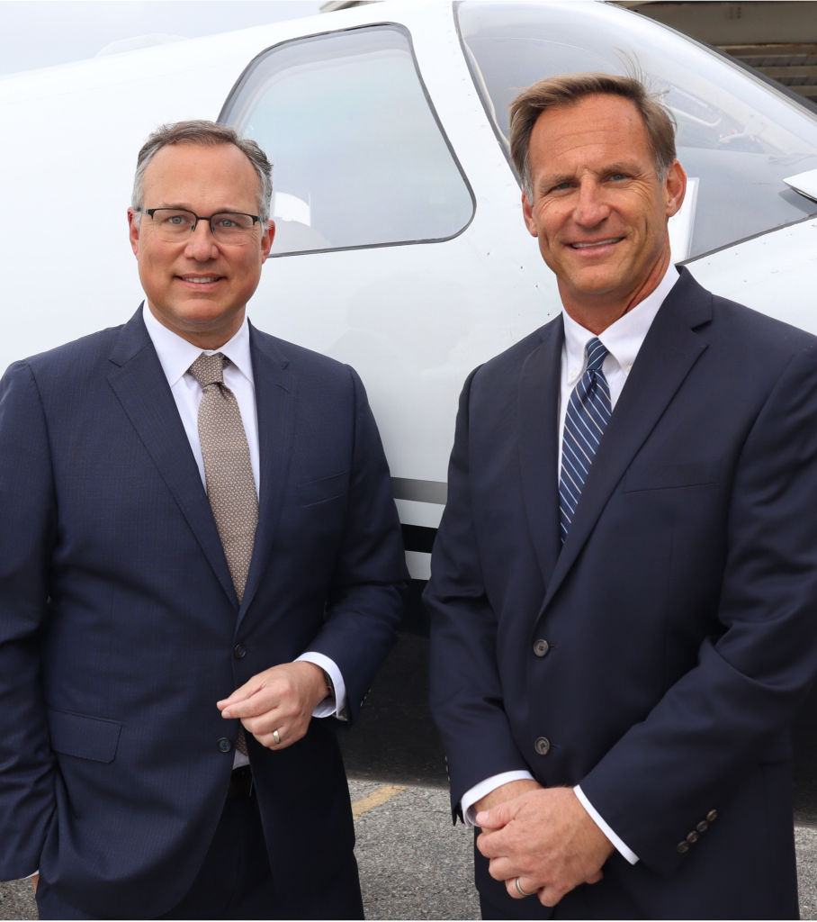 Picture of J.P. Dice (left) and Clay Sharpe (right) standing in front of a white plane